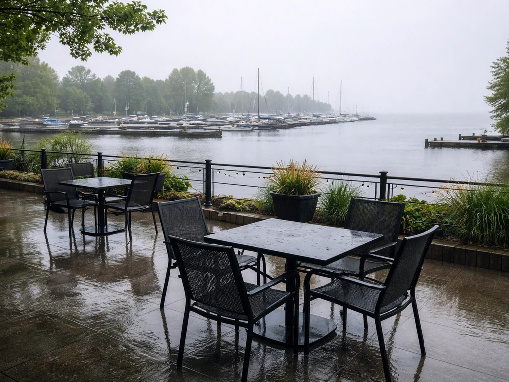 Empty lakeside marina patio with wet chairs and docks, overcast sky and calm harbor water